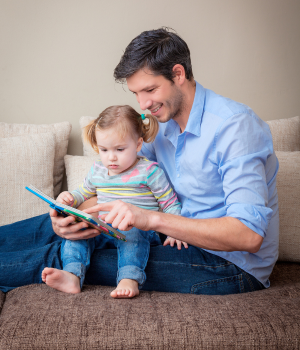 father reading book to toddler