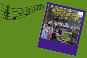 photograph of a band playing outside while people sit on the grass listening