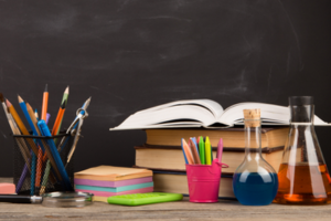 books, pens and scissors in front of a chalk board