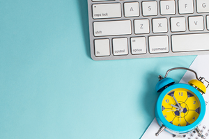 computer keyboard, multiple choice sheet and alarm clock on a light blue background