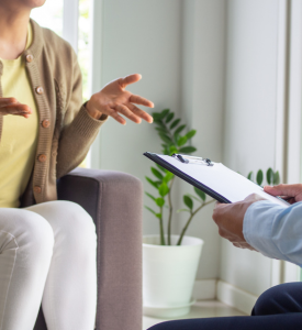 photograph of a person on a couch talking to a person holding a clipboard
