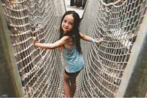 photograph of a young girl on a rope bridge