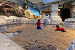 2 children in a sand pit looking for fossils