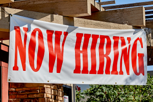 picture of a big white sign with the words Now Hiring