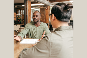 2 people sitting at a table speaking
