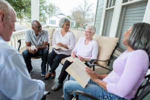 a group of people sitting outside on a porch holding books