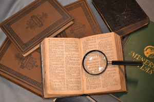 Historic books, one lying open with magnifying glass on top