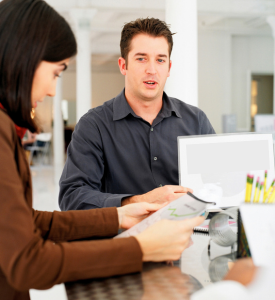 2 people sitting at a table with papers and a computer